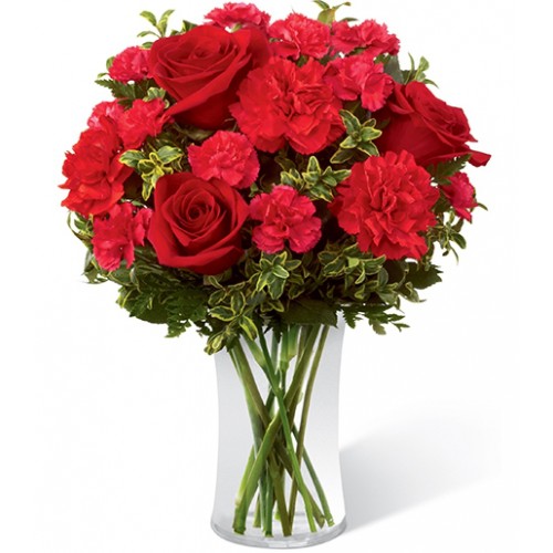Red roses accented with fuchsia mini carnations & lush greens arranged in clear glass vase to create exceptional way to convey love's tender message.