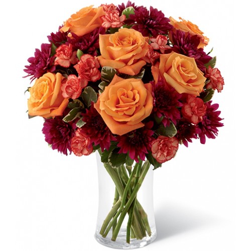 An eye-catching jewel tones - Brilliant orange roses and orange mini carnations accented with burgundy chrysanthemums and lush greens.